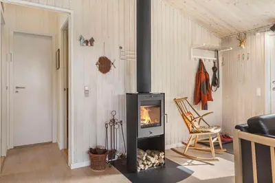 a living room with a fireplace and a chair at BL1466-Pandrup-Lunekrogen-14 in Pandrup