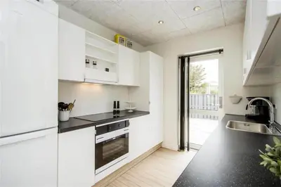 a kitchen with white cabinets and black counter tops at BL139-Blokhus-Klitvejen-4-A in Blokhus