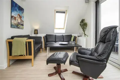 a living room with a leather chair and a table at BL139-Blokhus-Klitvejen-4-A in Blokhus