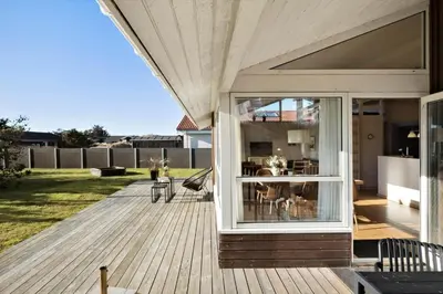 a house with a deck with a sliding glass door at BL222-Blokhus-Jens-Baerentsvej-16 in Blokhus