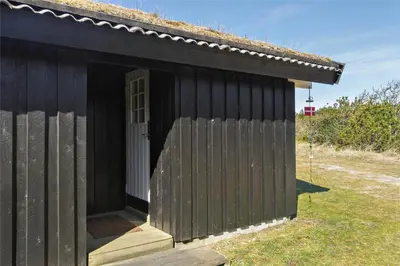 a black shed with a door and a fence at BL418-Pandrup-Hunetorp-Klitvej-141 in Pandrup