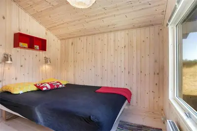 a small bedroom with a bed in a wooden wall at BL418-Pandrup-Hunetorp-Klitvej-141 in Pandrup