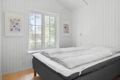 a bed in a white room with a window at BL1756-Blokhus-Bregnehojvej-7-A in Blokhus
