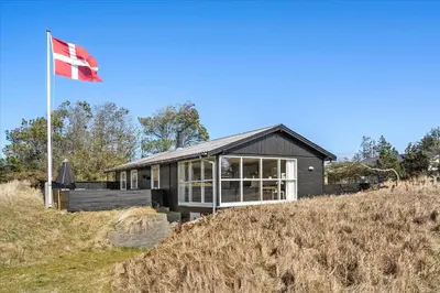 a house on top of a hill with a flag at BL1601-Blokhus-Kristinesvej-15 in Blokhus