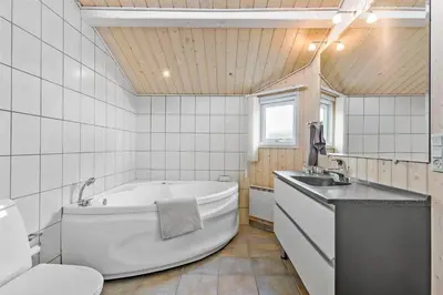 a bathroom with a tub and a toilet and a sink at BL1678-Pandrup-Hunetorp-Klitvej-1-B in Pandrup