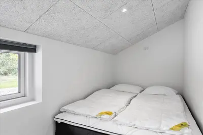 a bed in a white room with a window at BL1762-Blokhus-Bloksbjerg-22 in Blokhus