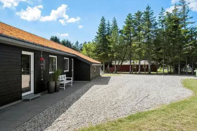 a house with a gravel driveway next to a building at BL1762-Blokhus-Bloksbjerg-22 in Blokhus
