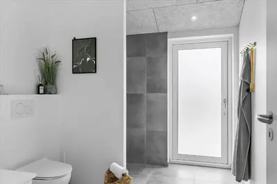 a bathroom with a white toilet and a door at BL1762-Blokhus-Bloksbjerg-22 in Blokhus