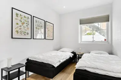 two beds in a white room with pictures on the wall at BL1520-Blokhus-Klitgaardsvej-3-B in Blokhus