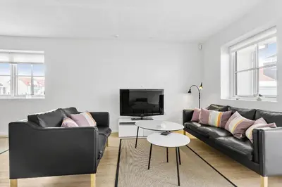 a living room with two black couches and a tv at BL1520-Blokhus-Klitgaardsvej-3-B in Blokhus