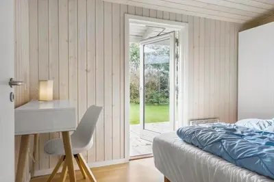 a bedroom with a bed and a desk and a window at BL1152-Blokhus-Septimusvej-28 in Blokhus