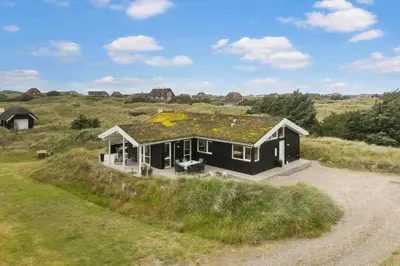 a black house with a roof with yellow flowers on it at BL1564-Blokhus-Ved-Skoven-8 in Blokhus