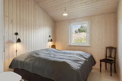 a bedroom with a bed and a window at BL1564-Blokhus-Ved-Skoven-8 in Blokhus