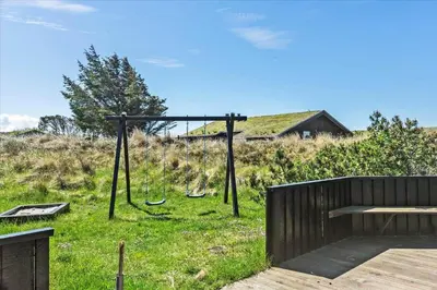 a swing set on a grassy hill with a house at BL411-Pandrup-Hunetorp-Klitvej-223 in Pandrup