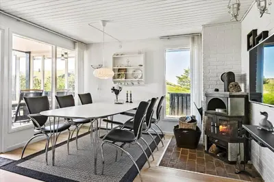 a dining room with a table and chairs and a fireplace at BL411-Pandrup-Hunetorp-Klitvej-223 in Pandrup