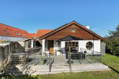 a house with a deck with chairs and an umbrella at BL1527-Blokhus-Svinget-5 in Blokhus