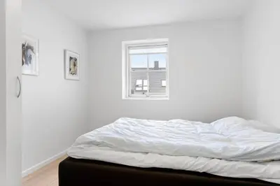 an unmade bed in a white room with a window at BL1222-Blokhus-Strandvejen-13-B in Blokhus