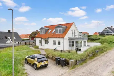 a yellow car parked in front of a white house at BL1222-Blokhus-Strandvejen-13-B in Blokhus