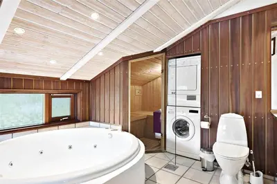 a bathroom with a tub and a washing machine at BL236-Blokhus-Pirupshvarrevej-27 in Blokhus