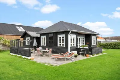 a black house with a table and chairs in a yard at BL1612-Blokhus-Jens-Baerentsvej-3 in Blokhus