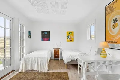 a white bedroom with two beds and a desk at BL1612-Blokhus-Jens-Baerentsvej-3 in Blokhus