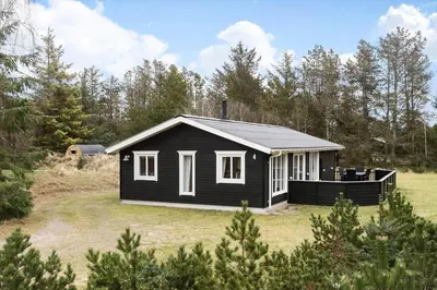a small black house in a yard with trees at BL1286-Saltum-Lyngsletten-4 in Saltum