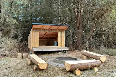 a wooden dog house with a fire pit in the woods at BL969-Blokhus-Bregnehojvej-16 in Blokhus