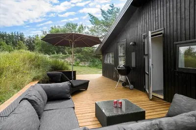 a patio with a couch and an umbrella and a grill at BL1315-Saltum-Kordalsvej-43 in Saltum
