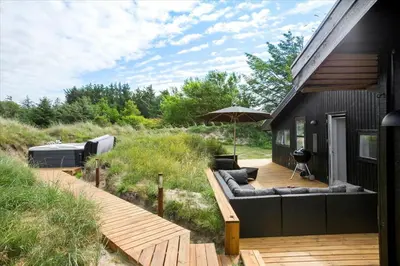 a deck with a couch and an umbrella on a house at BL1315-Saltum-Kordalsvej-43 in Saltum
