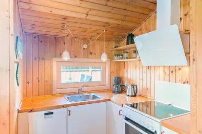 a kitchen with wooden walls and a sink and a stove at BL469-Pandrup-Hunetorp-Klitvej-179 in Pandrup