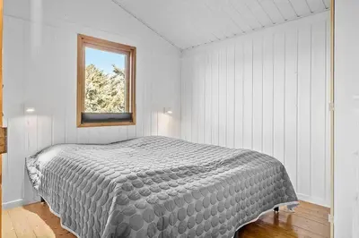 a white bedroom with a bed with a window at BL1616-Blokhus-Moreavej-18 in Blokhus