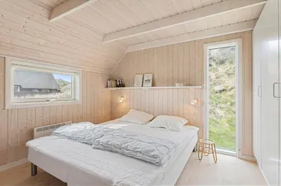a bedroom with a bed in a room with a window at BL830-Pandrup-Bardehvalen-3 in Pandrup
