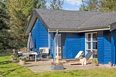 a blue house with a patio and a table at BL1328-Saltum-Kvanbaekvej-33 in Saltum