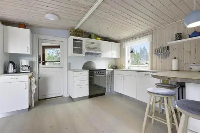 a kitchen with white cabinets and a wooden ceiling at BL1447-Blokhus-Skraavejen-11 in Blokhus