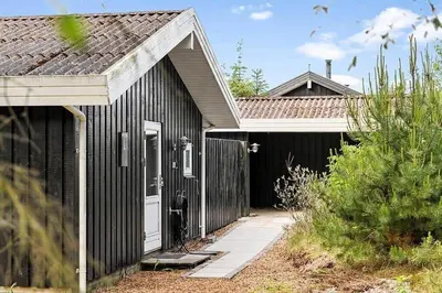a black house with a white door and a fence at BL1654-Saltum-Ornebjergvej-11 in Saltum