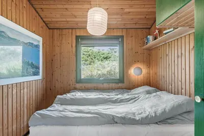 a bedroom with a large bed in a wooden wall at BL1473-Pandrup-Lommelaerken-14 in Pandrup