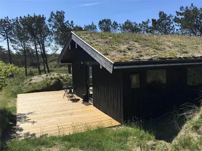 a building with a grass roof with a wooden deck at BL1473-Pandrup-Lommelaerken-14 in Pandrup