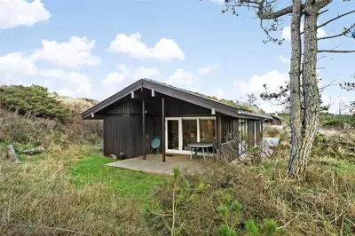 a small black house with a wooden deck at BL1473-Pandrup-Lommelaerken-14 in Pandrup