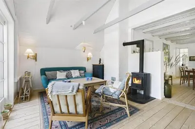 a living room with a table and a fireplace at BL1384-Blokhus-Kragebak-7 in Blokhus