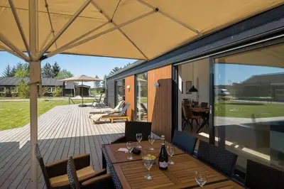 a patio with a wooden table with wine glasses at BL1257-Saltum-Vesterhavs-Sletten-35 in Saltum