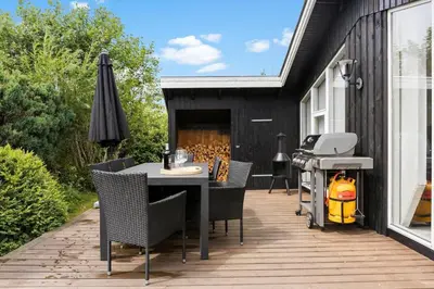 a patio with a table and chairs and a grill at BL1218-Blokhus-Quintusvej-24 in Blokhus