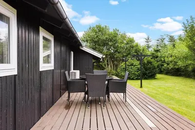 a wooden deck with a table and chairs on it at BL1218-Blokhus-Quintusvej-24 in Blokhus