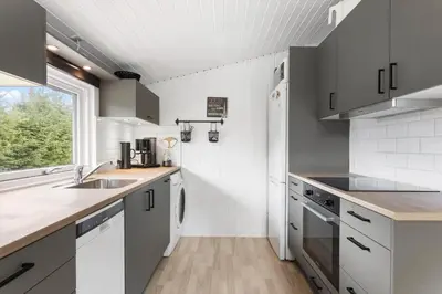 a kitchen with white cabinets and a sink and a window at BL1218-Blokhus-Quintusvej-24 in Blokhus