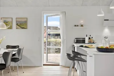 a white kitchen with black chairs and a table at BL1355-Blokhus-Ribergaardsvej-24 in Blokhus