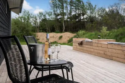 a bottle of wine and glasses on a table on a patio at BL1355-Blokhus-Ribergaardsvej-24 in Blokhus