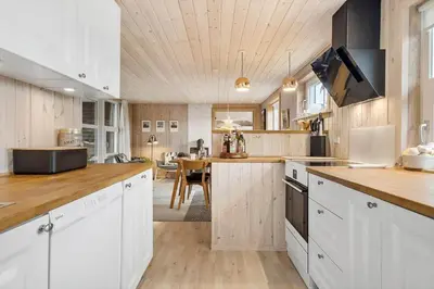 a kitchen with white cabinets and a dining room at BL709-Blokhus-Kr-Thomsensvej-5 in Blokhus
