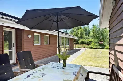a table with a black umbrella on a patio at BL1727-Pandrup-Lunekrogen-16 in Pandrup