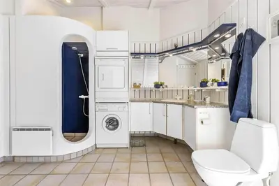 a white bathroom with a toilet and a sink at BL1534-Blokhus-Taarnfalkevej-10 in Blokhus