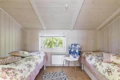 a room with two beds and a chair in it at BL1534-Blokhus-Taarnfalkevej-10 in Blokhus