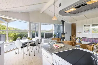 a kitchen and living room with a table and chairs at BL1534-Blokhus-Taarnfalkevej-10 in Blokhus
